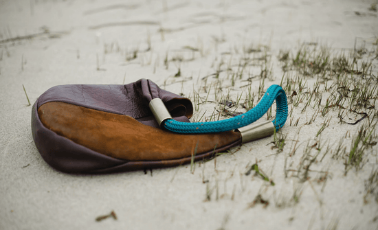 leather bag with teal rope on the beach