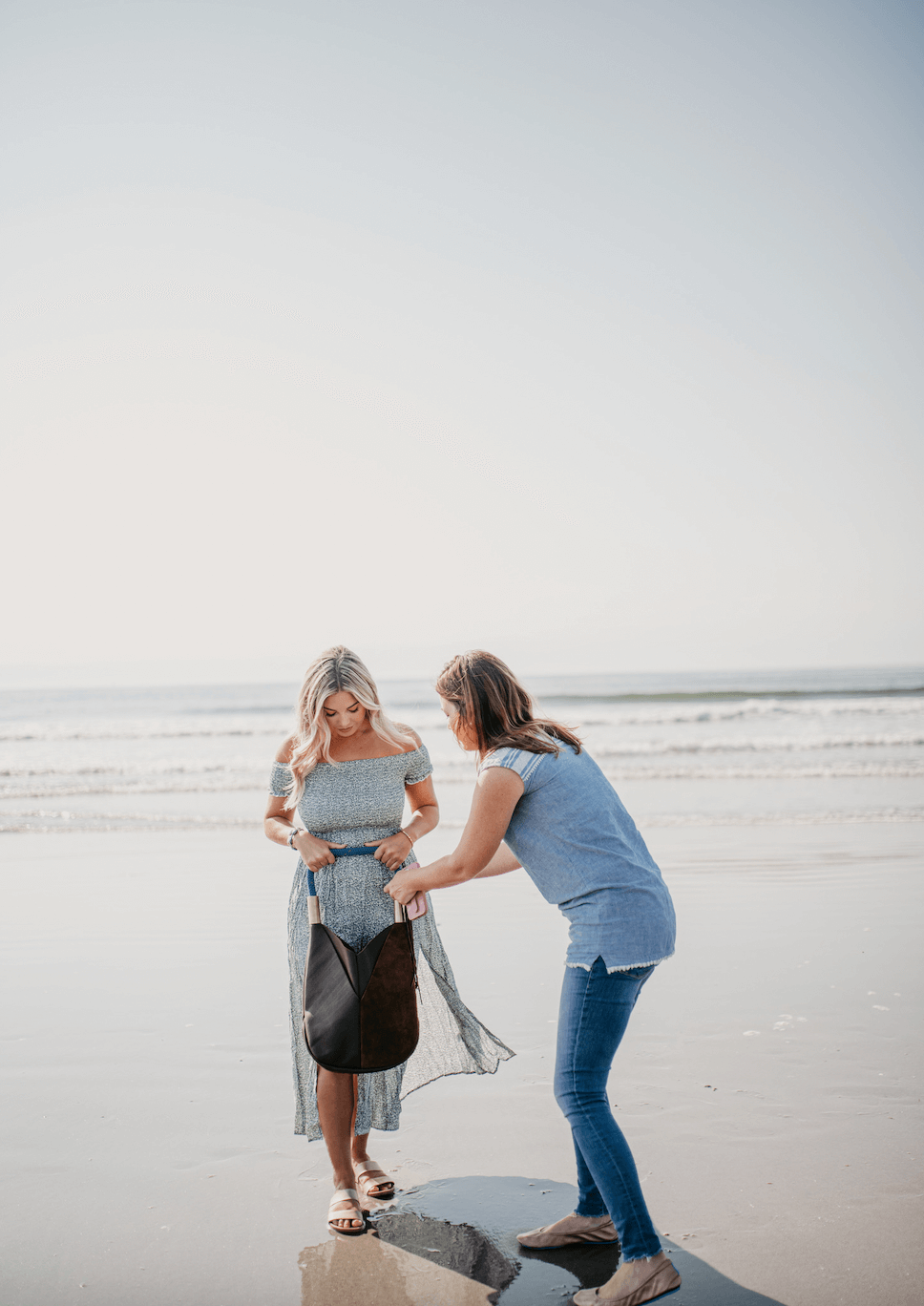 woman adjusting handbag on model at the beach