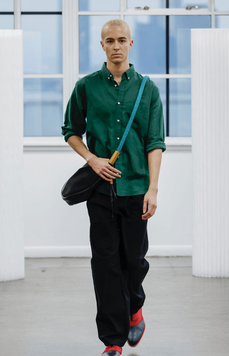 man wearing a black leather crossbody with teal rope strap