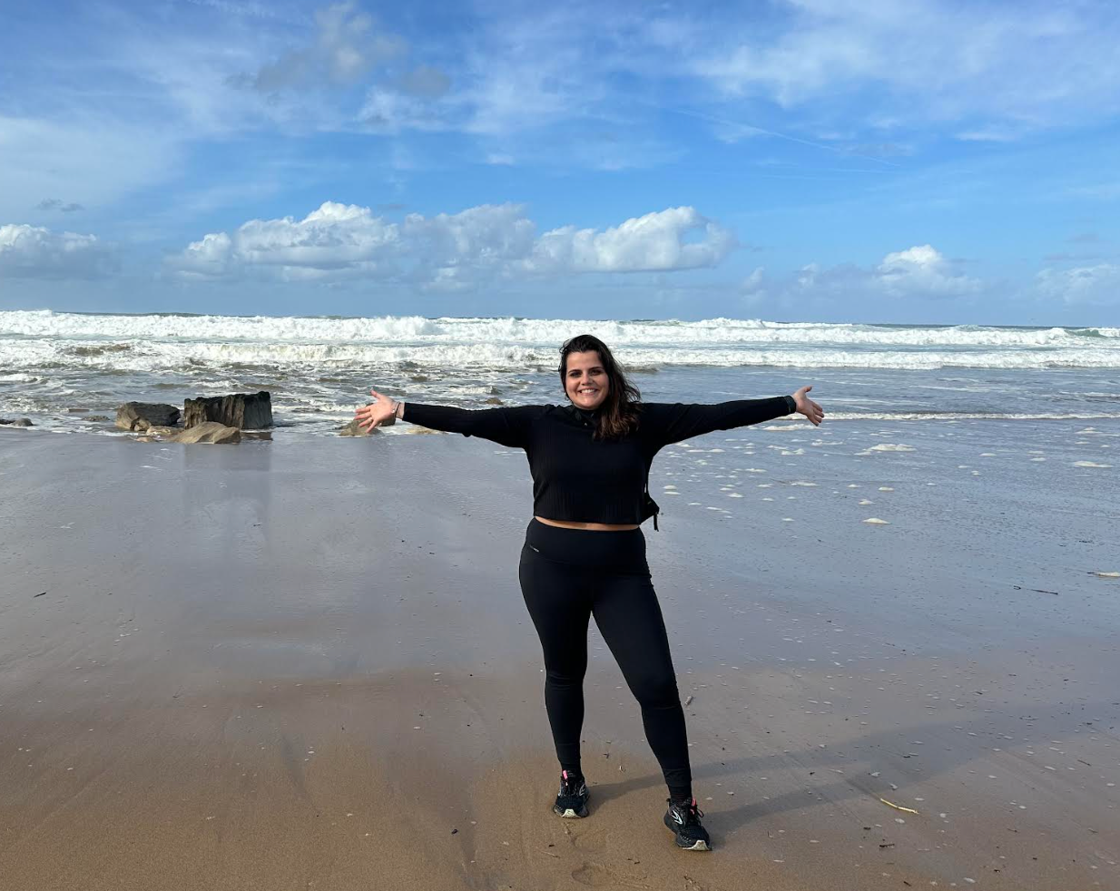 woman holding up her arms at the beach