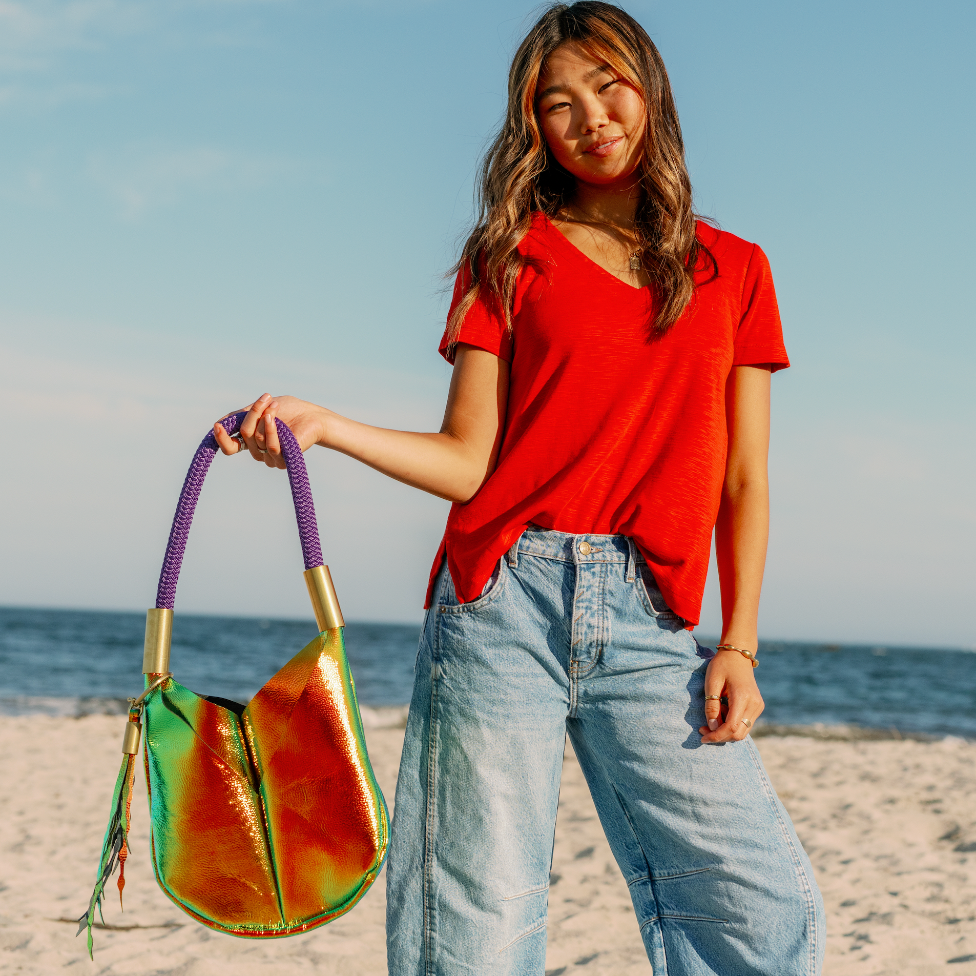 Woman holding a colorful handbag on a beach