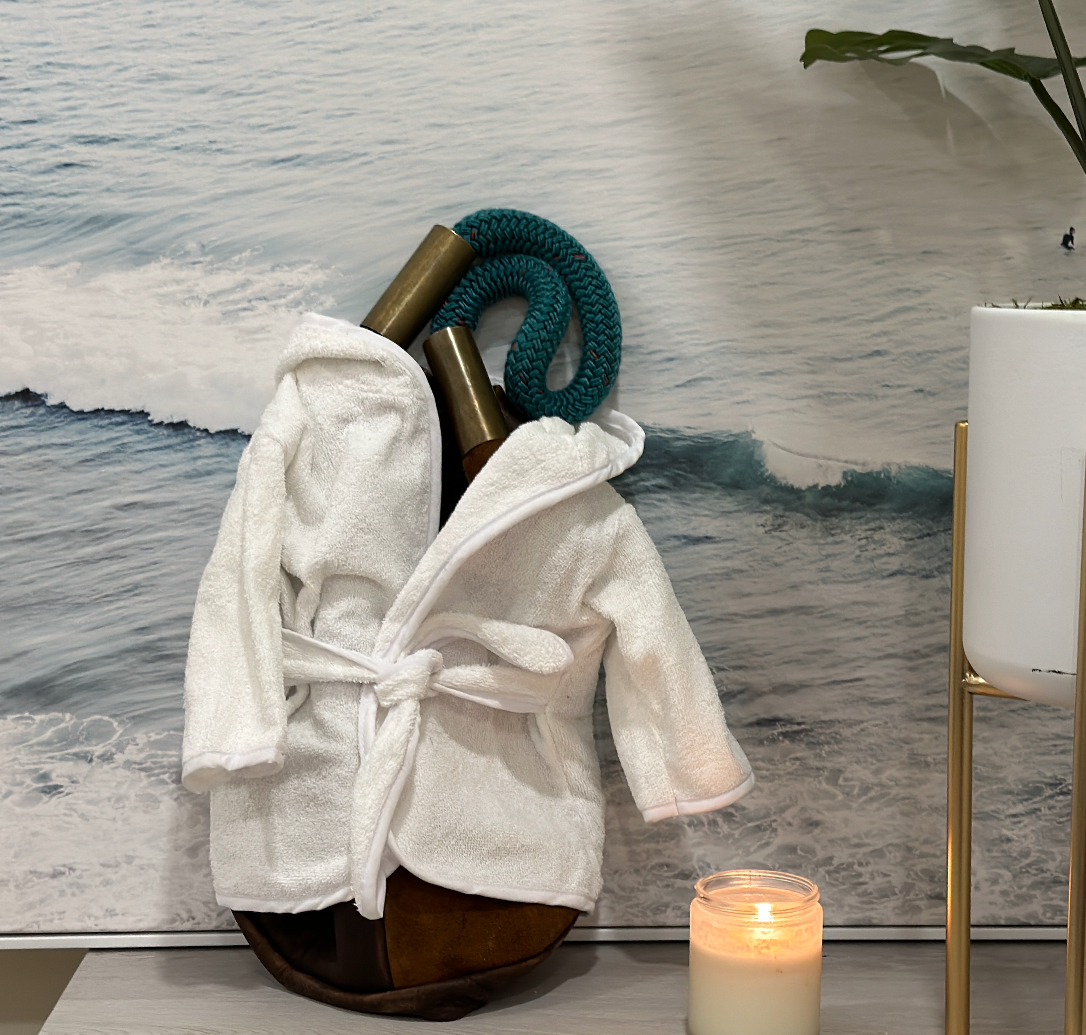 White robe on a stand with a candle and decorative items against a marble wall.