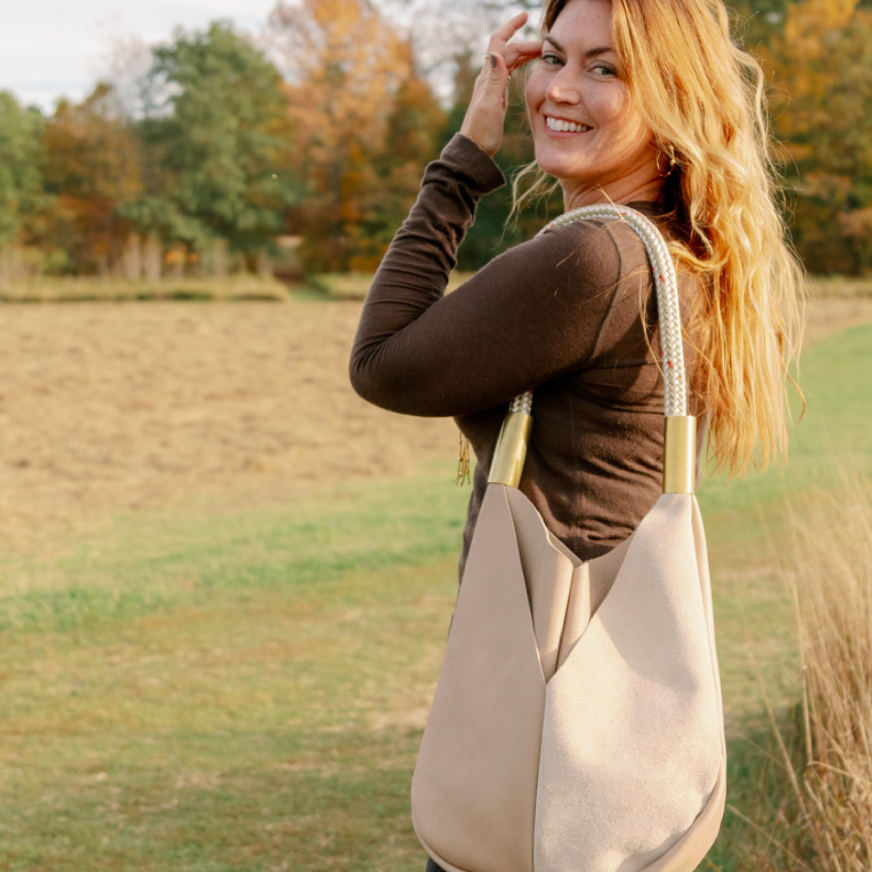 Woman holding a beige tote bag outdoors in a natural setting