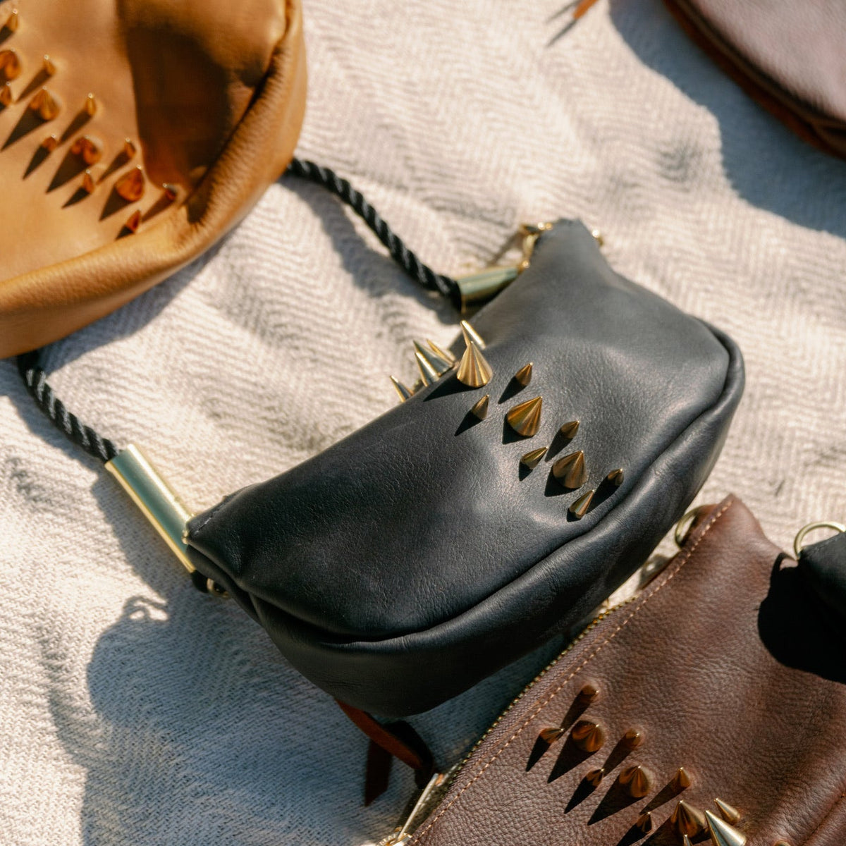 Bags on a blanket focused on the Black Convertible Sea Urchin Bag