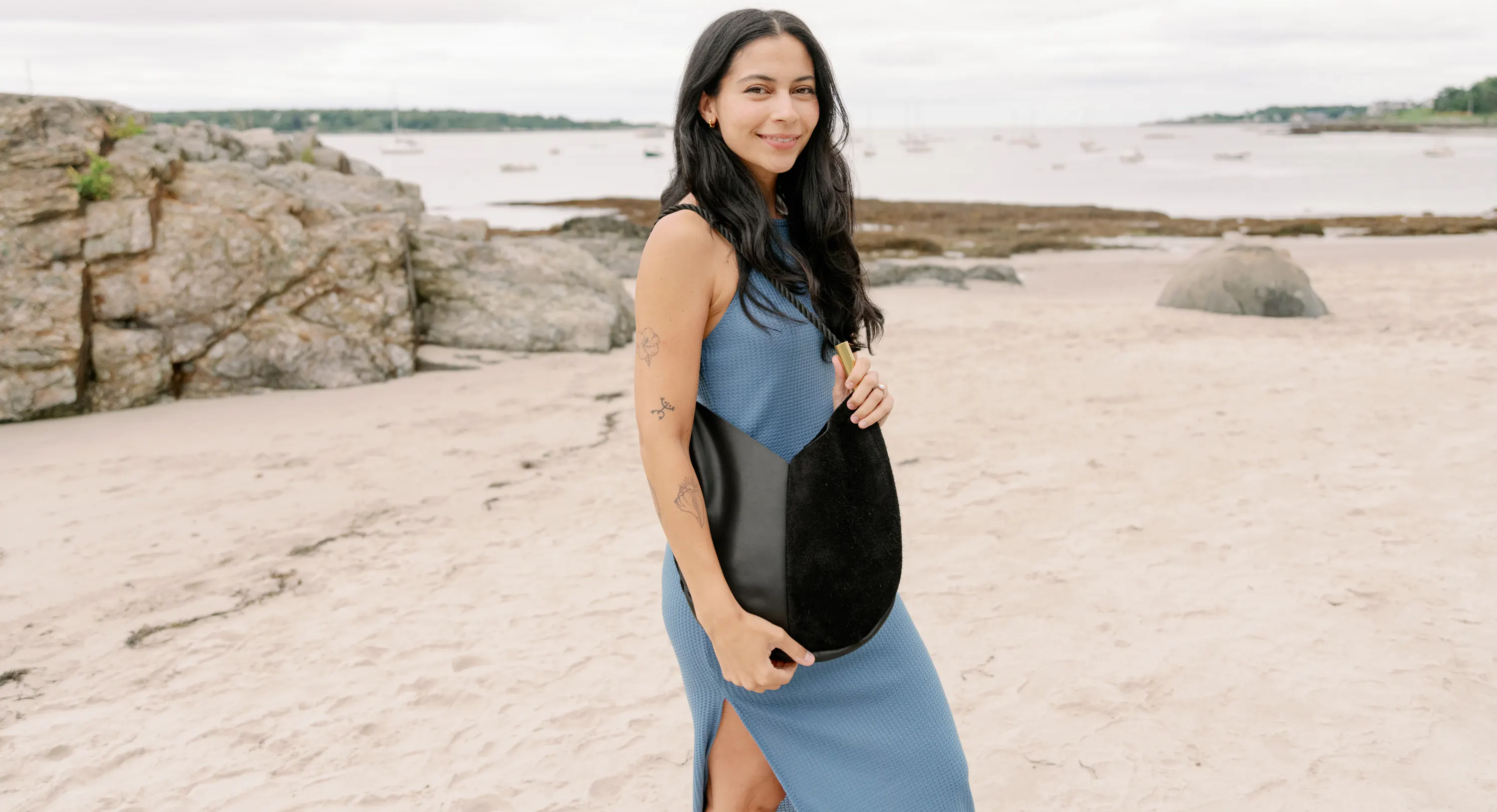 black leather and suede bag worn by a woman on the beach