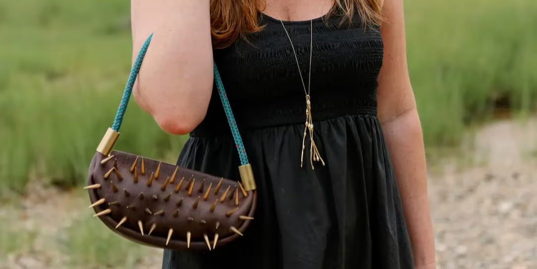 brown leather bag with a teal handle and spiky studs