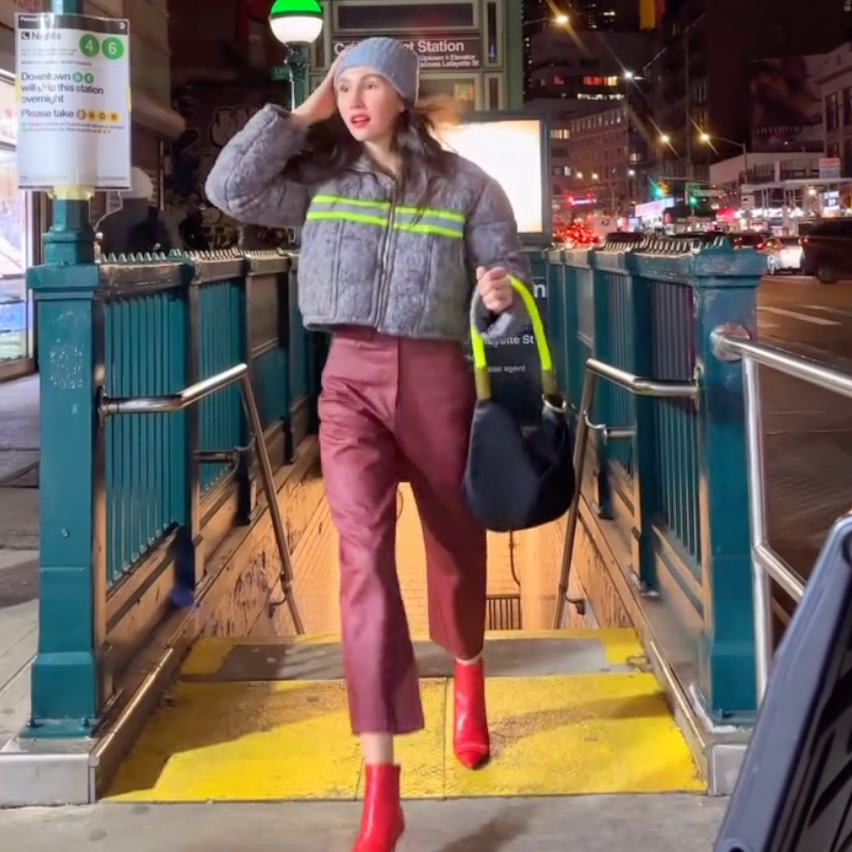 Person walking on a city street at night with colorful lights in the background