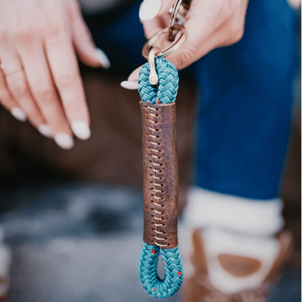Close-up of a hand holding a keychain with a blue rope design.
