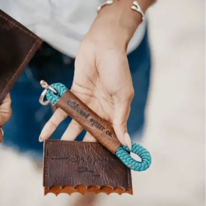 Person holding a leather wallet with a blue rope keychain, brand 'Vilkenkind' visible.