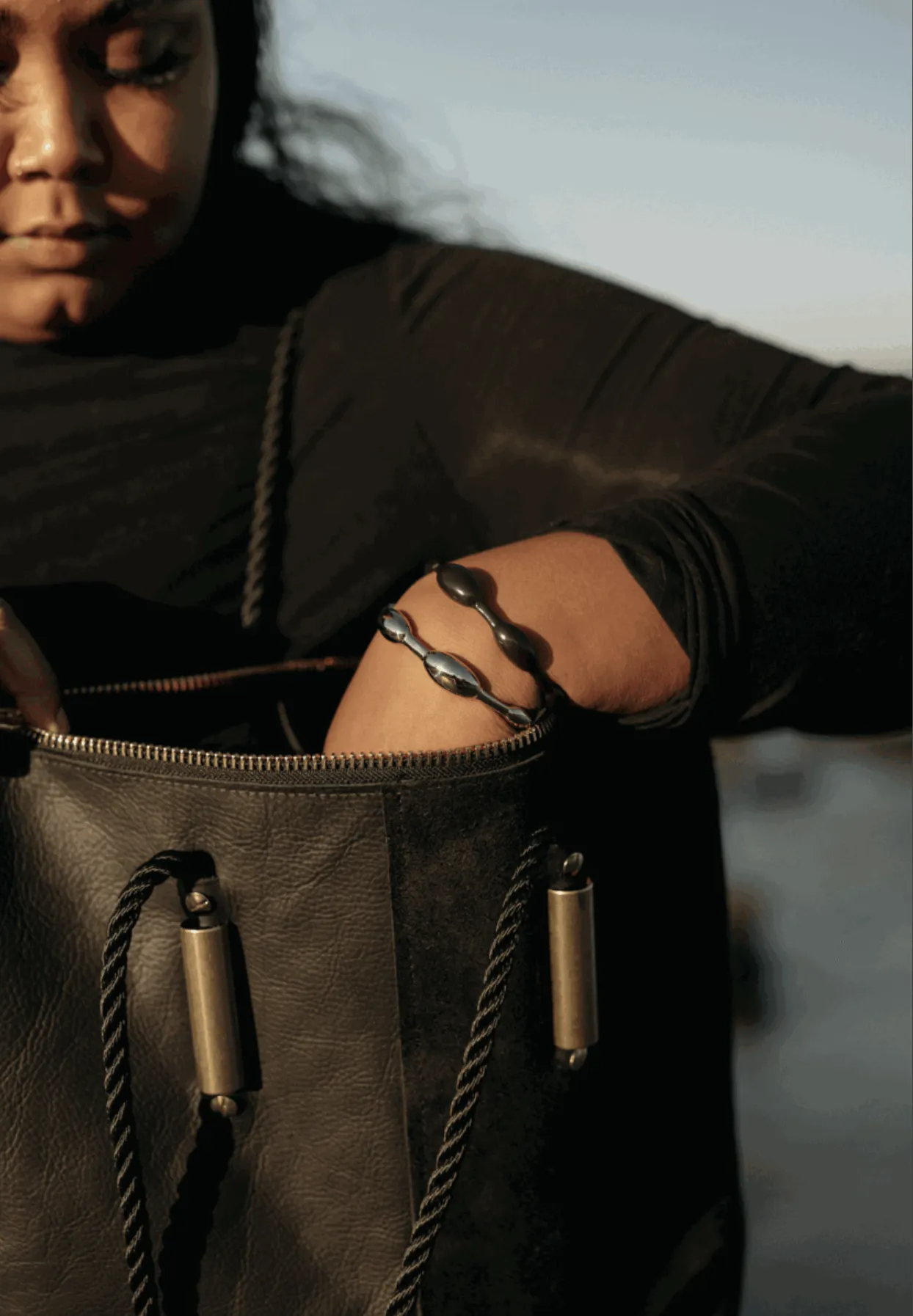 woman reaching inside a black leather bag