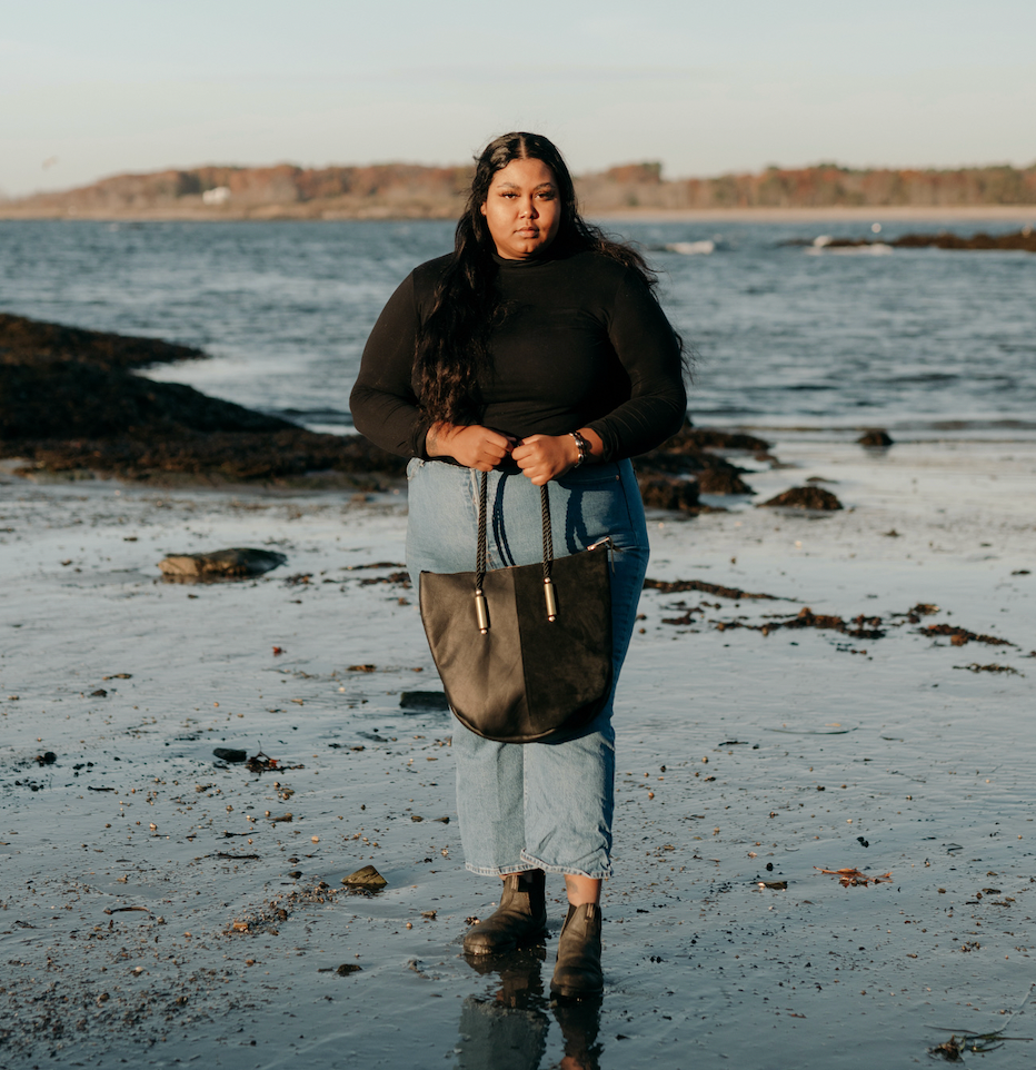 woman on the beach wearing a black leather and suede tote