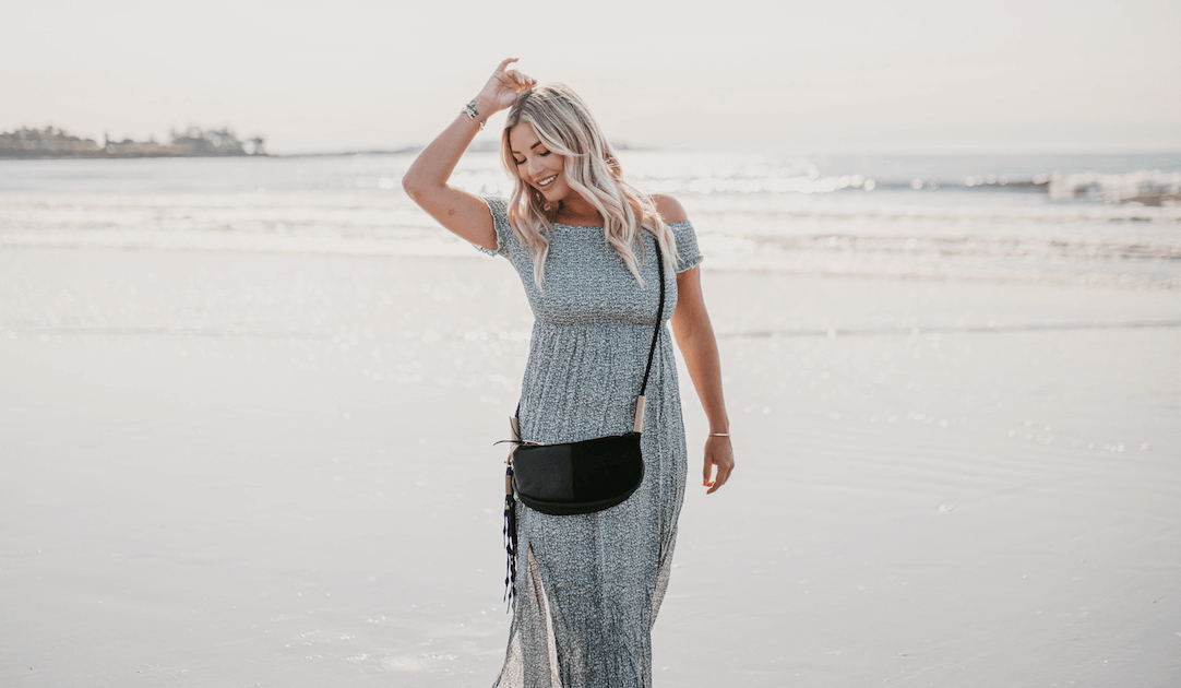 Woman on the beach wearing black leather zip crossbody bag