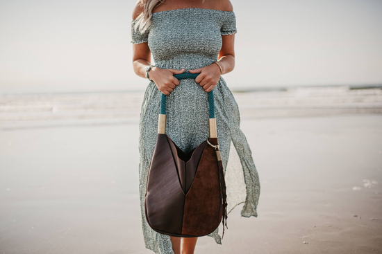 woman holding brown leather bag on the beach