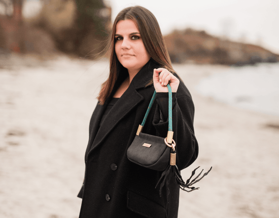 woman wearing a black coat and black bag on the beach