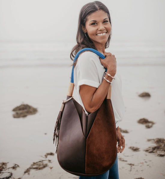 woman wearing a brown leather tote on the beach