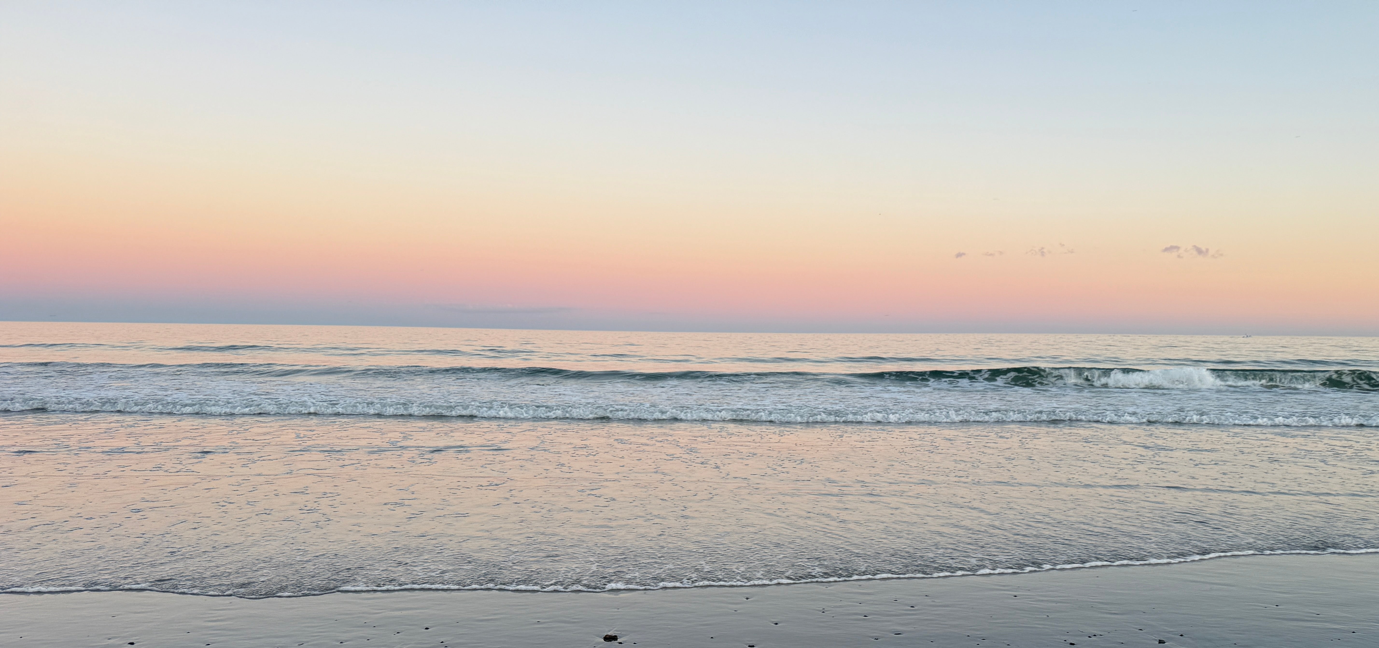 Beach at sunset with calm ocean and clear sky