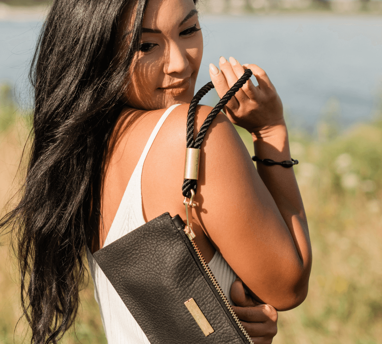 woman holding a black leather clutch over her shoulder