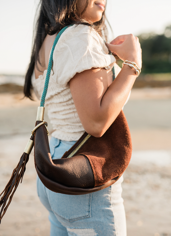 woman wearing brown leather sling bag with seaweed tassel