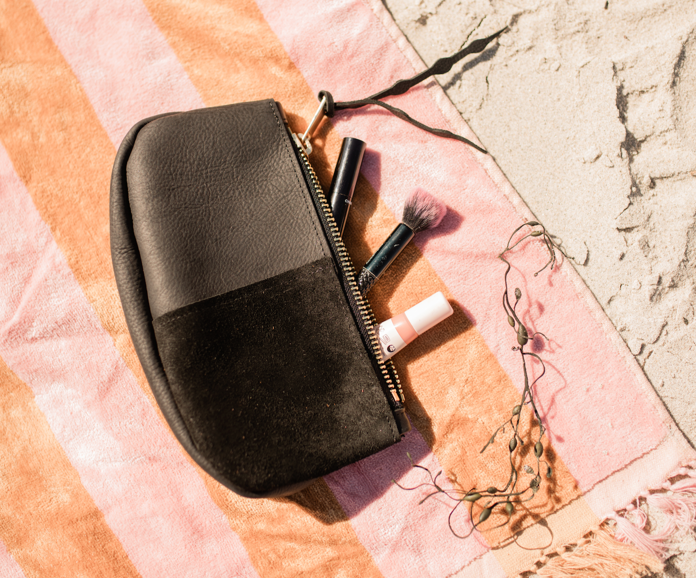 black leather makeup bag on beach blanket