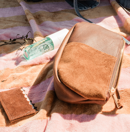 brown leather accessories on beach blanket