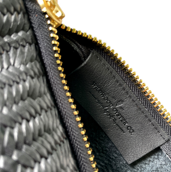 closeup of wildwood label inside black basketweave leather bag