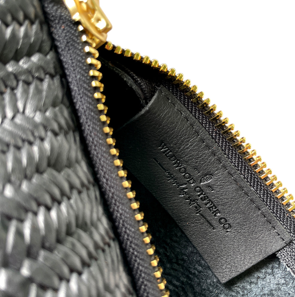 closeup up of wildwood oyster co label inside black basketweave leather bag