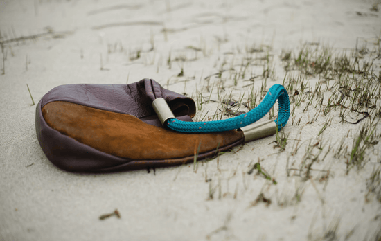 brown leather bag resting on the beach