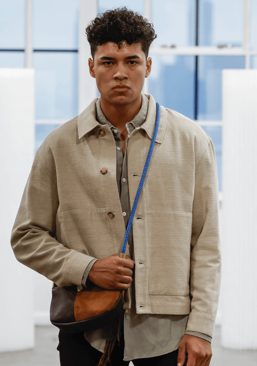 man wearing a brown leather crossbody with a blue strap