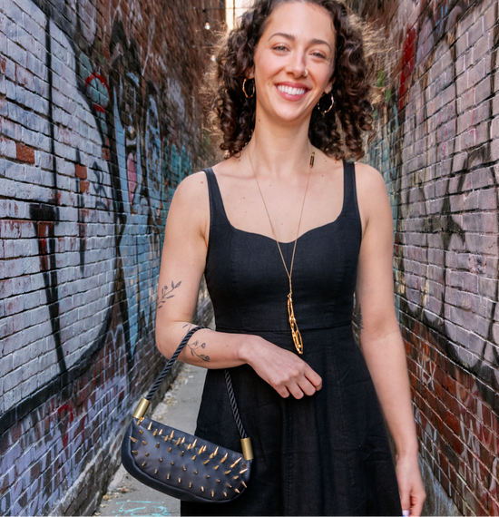 Woman in a black dress standing in front of a graffiti-covered wall