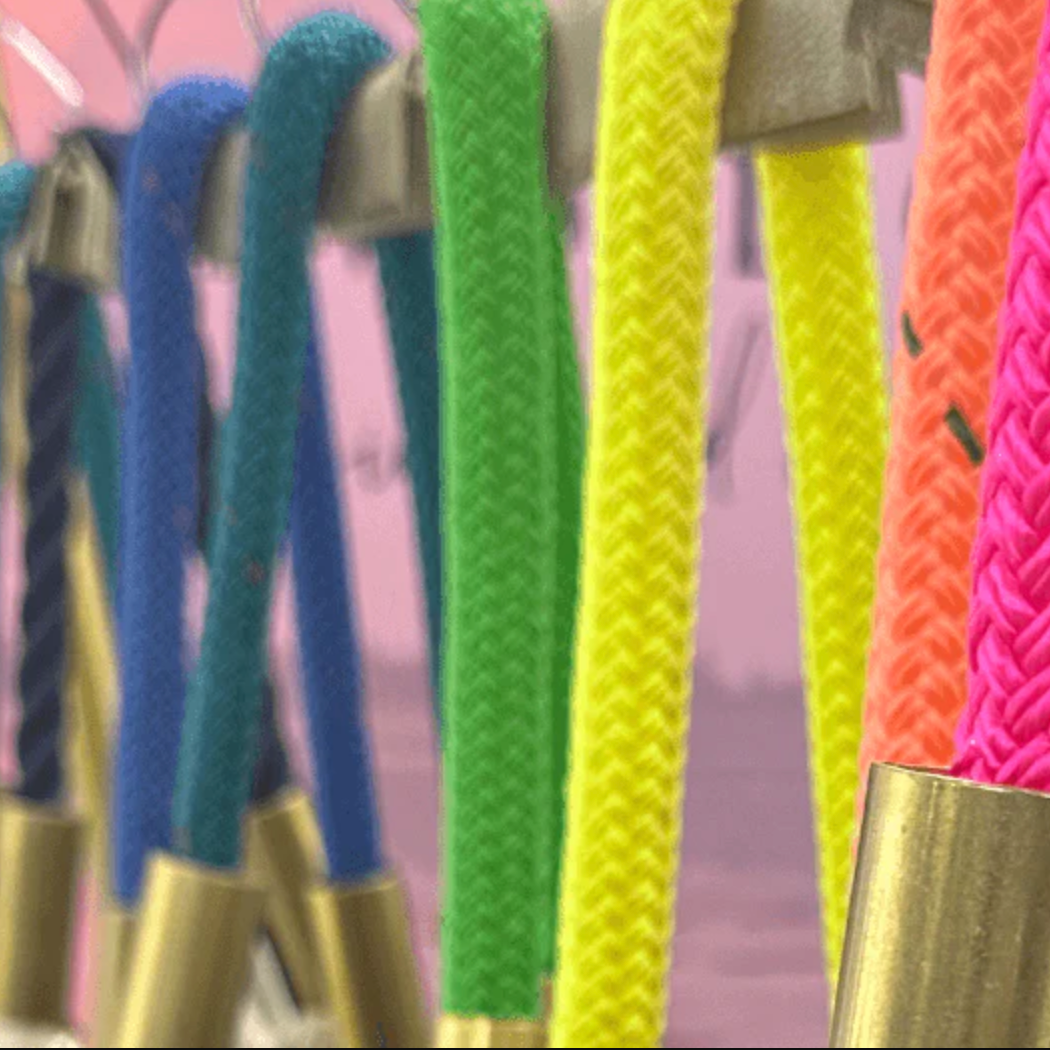 Colorful braided handles on a stand with a blurred outdoor background