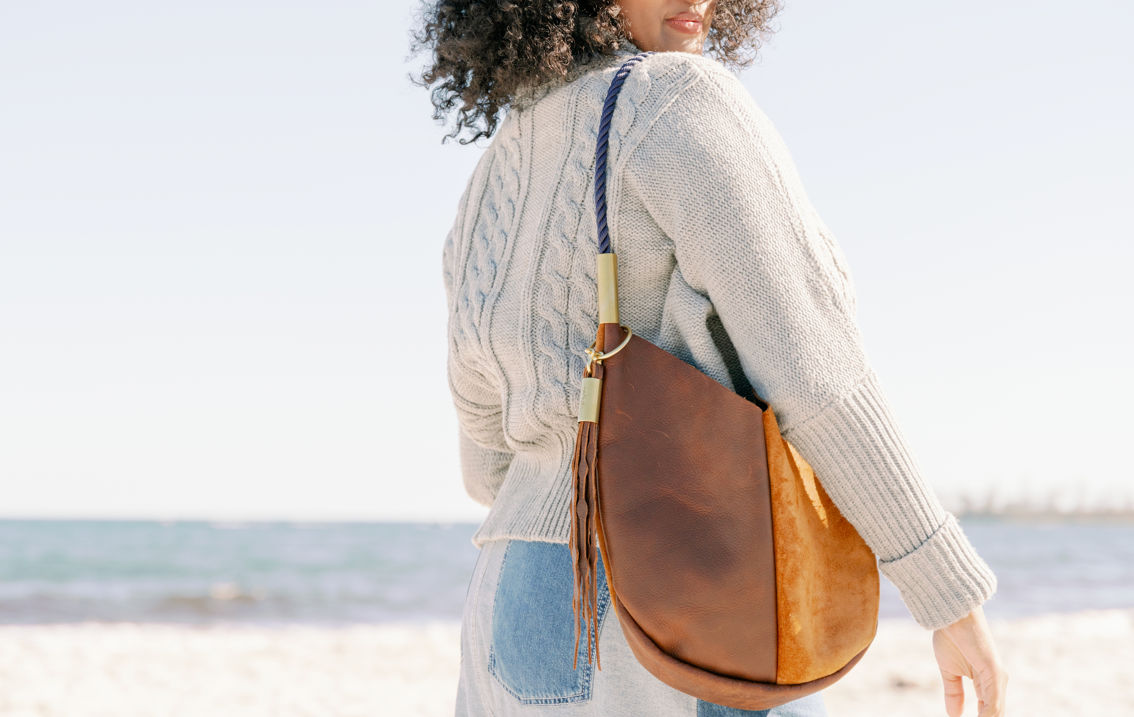 Woman carrying a brown leather bag on a beach
