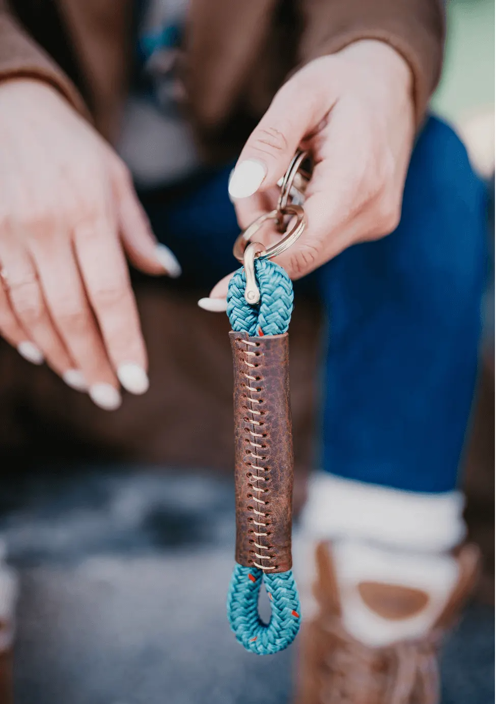 Close-up of a hand holding a keychain with a blue rope design.