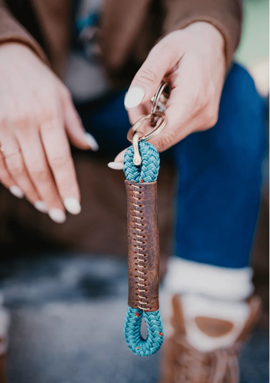 Close-up of a hand holding a keychain with a blue rope design.
