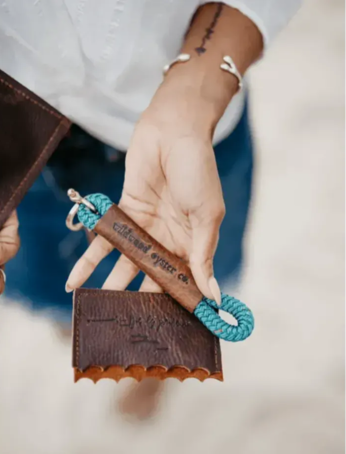 Person holding a leather wallet with a blue rope keychain, brand 'Vilkenkind' visible.